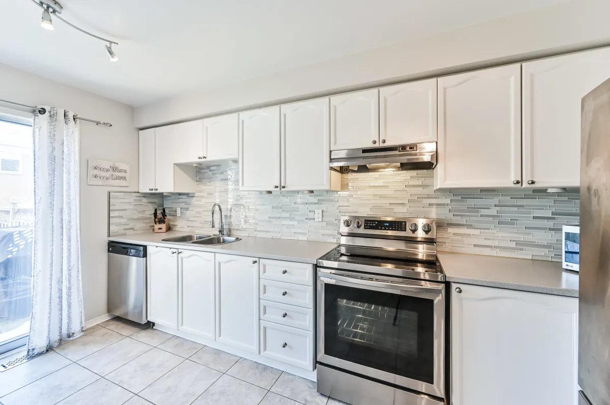 Modern white kitchen at 133 Howard Crescent with stainless steel appliances and ample cabinetry.