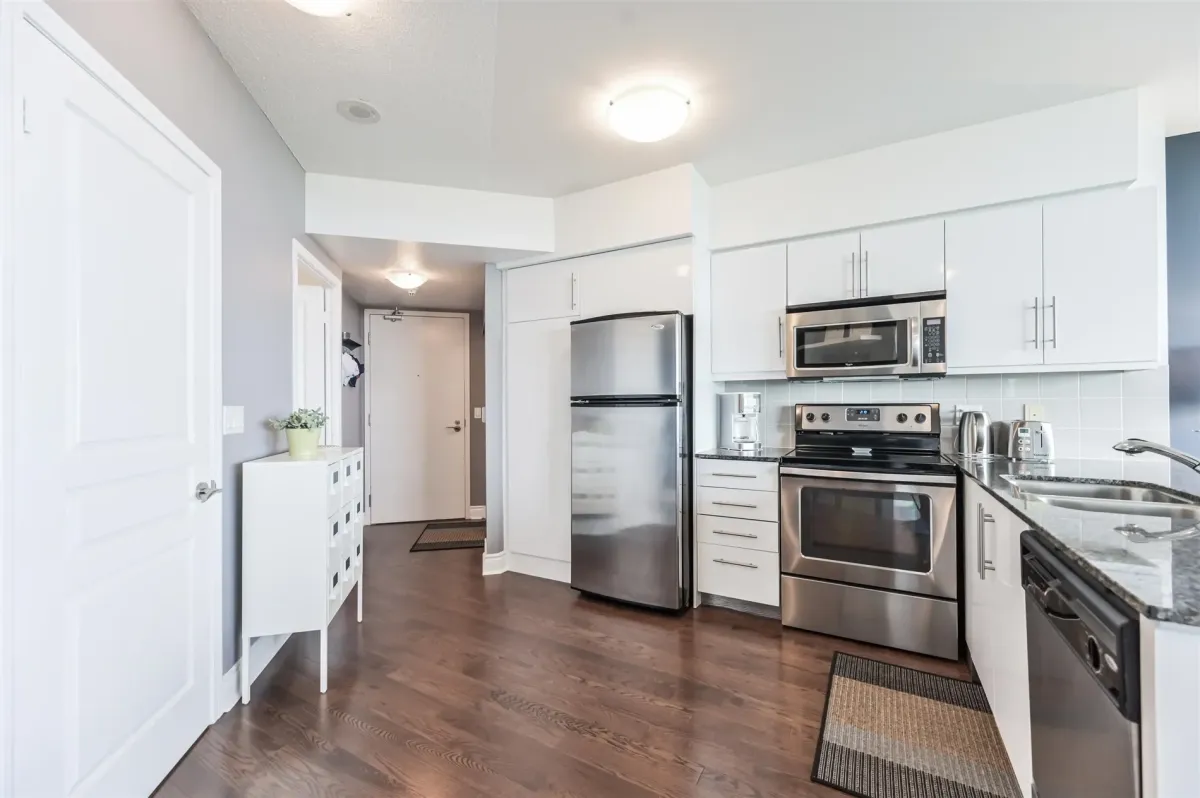 Modern kitchen featuring granite countertops, stainless steel appliances, and light cabinetry.