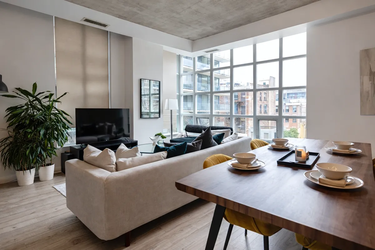 Bright open-concept living room in suite 305 at 23 Brant featuring floor-to-ceiling windows and hardwood floors.
