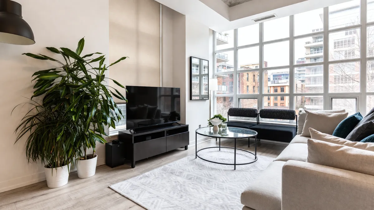 Bright open-concept living room in suite 305 at 23 Brant featuring floor-to-ceiling windows and hardwood floors.