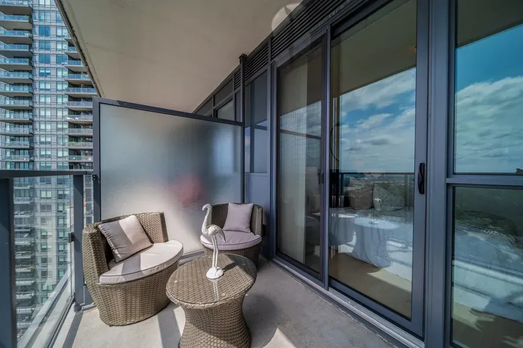 Close-up of the outdoor seating area on the 34th-floor balcony of 10 Park Lawn Rd, Unit 3402 overlooking the city.