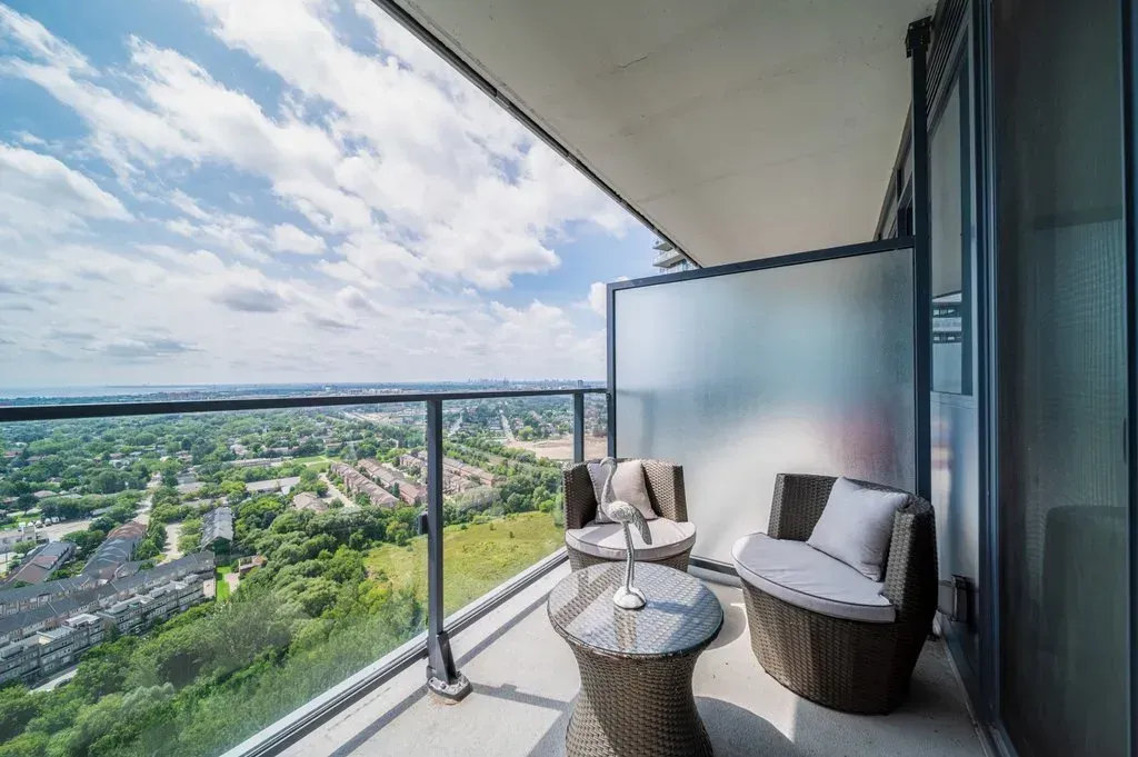 Modern glass-railed balcony at 10 Park Lawn Rd, Unit 3402 with outdoor seating and expansive green views.