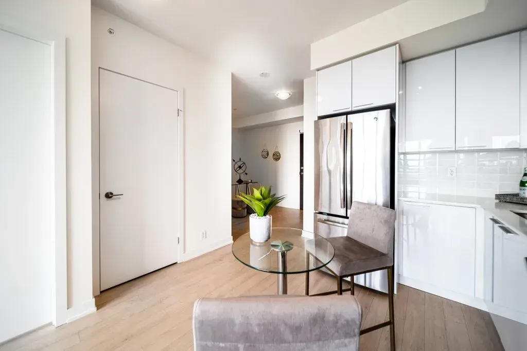 View from the hallway into the bright, modern kitchen of 10 Park Lawn Rd, Unit 3402 with track lighting.