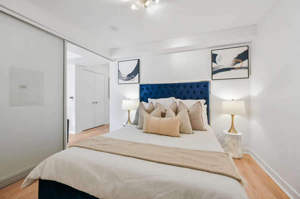Spacious bedroom at 100 Western Battery Rd, Unit 1911 with a navy blue velvet headboard and large windows.