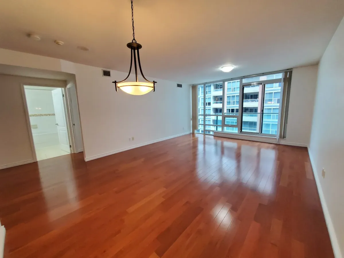 Oversized open-concept living room at 263 Wellington St W, Unit 701 featuring gleaming hardwood floors and floor-to-ceiling windows.