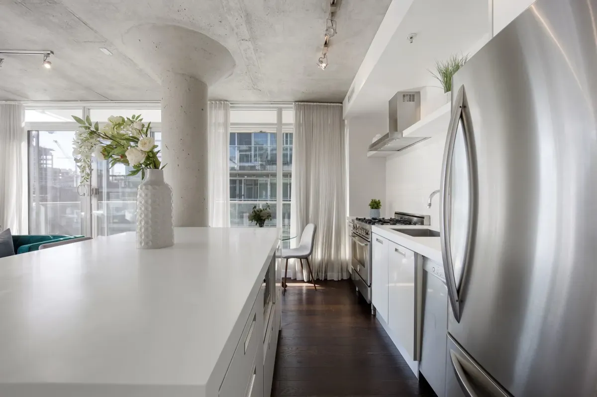 Modern chef’s kitchen in suite #807 at 75 Portland St, showing the seamless flow into the living area and floor-to-ceiling windows.