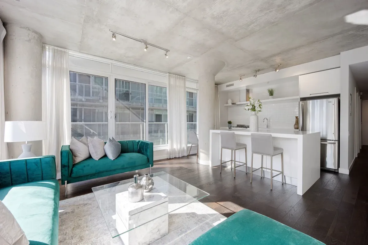 Wide-angle view of the living and dining space at 75 Portland St #807, featuring soft loft industrial-chic concrete ceilings.