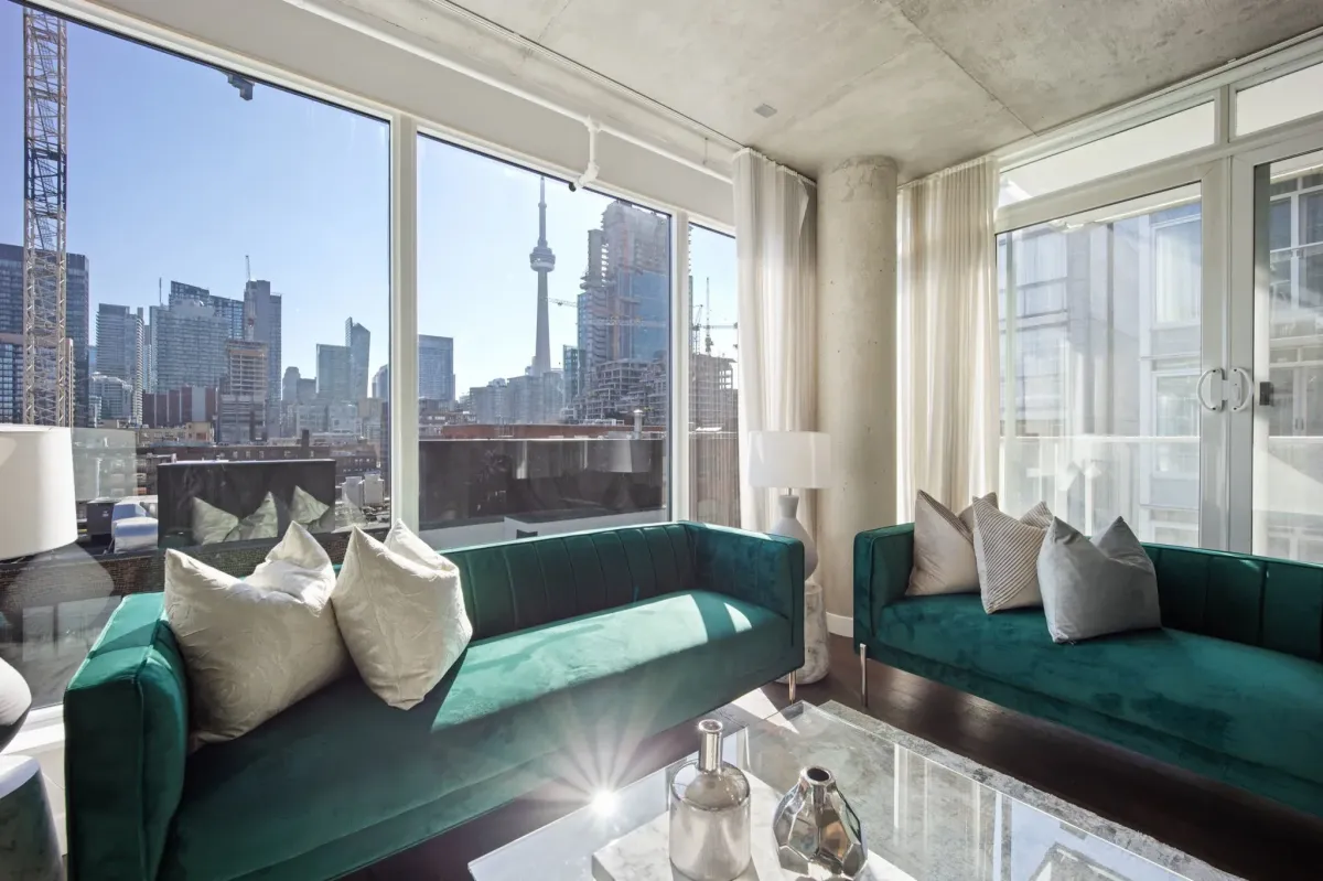 Elegant living area at 75 Portland St #807, showing the emerald green velvet seating and panoramic downtown views.