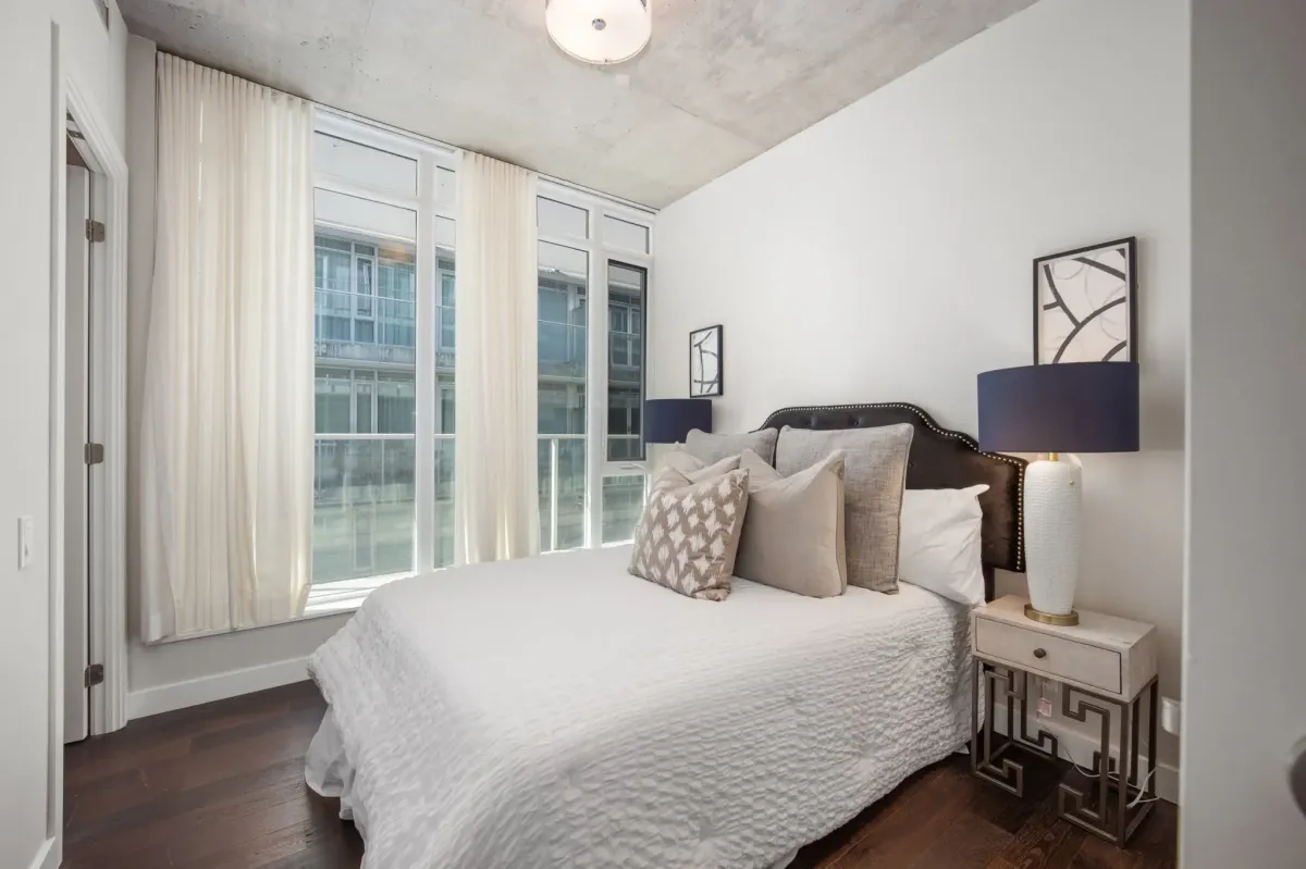 Bright, spacious bedroom at 75 Portland St #807 with floor-to-ceiling glass and sleek pre-engineered hardwood flooring.