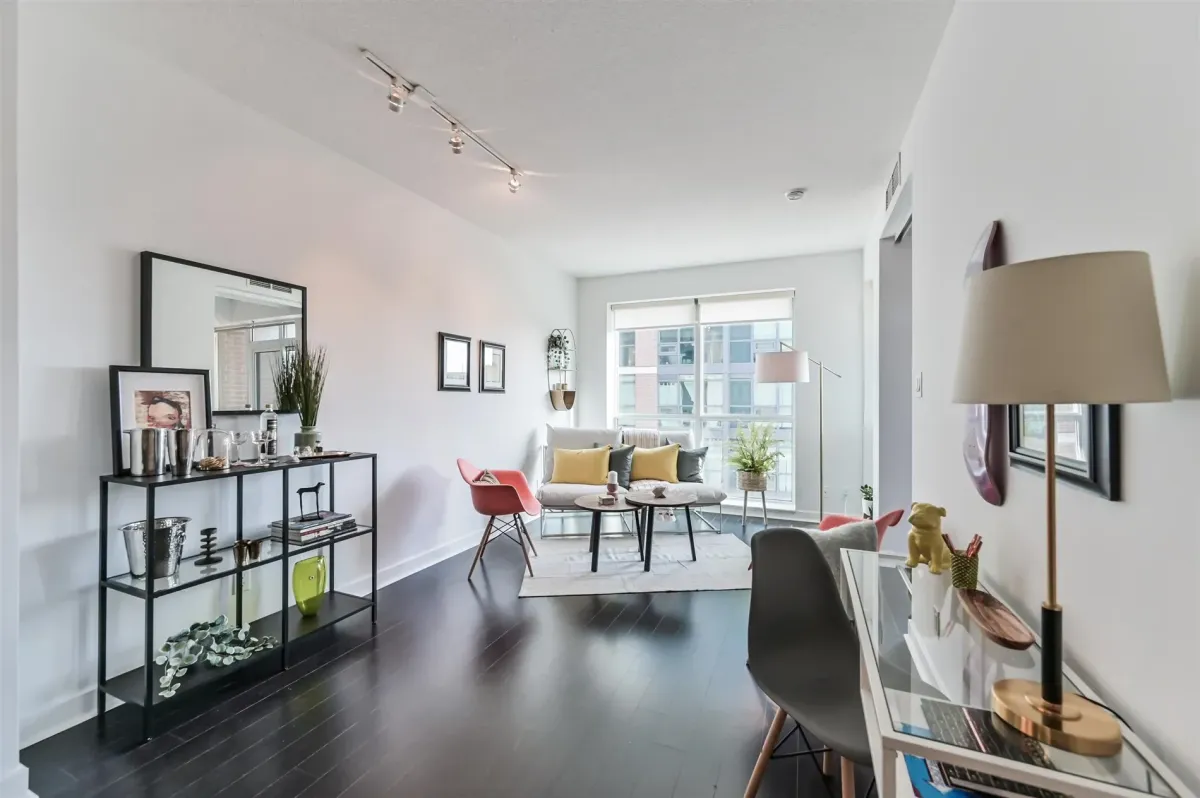Sun-drenched living area at 1169 Queen St W, Unit N502, with floor-to-ceiling windows and exposed concrete.