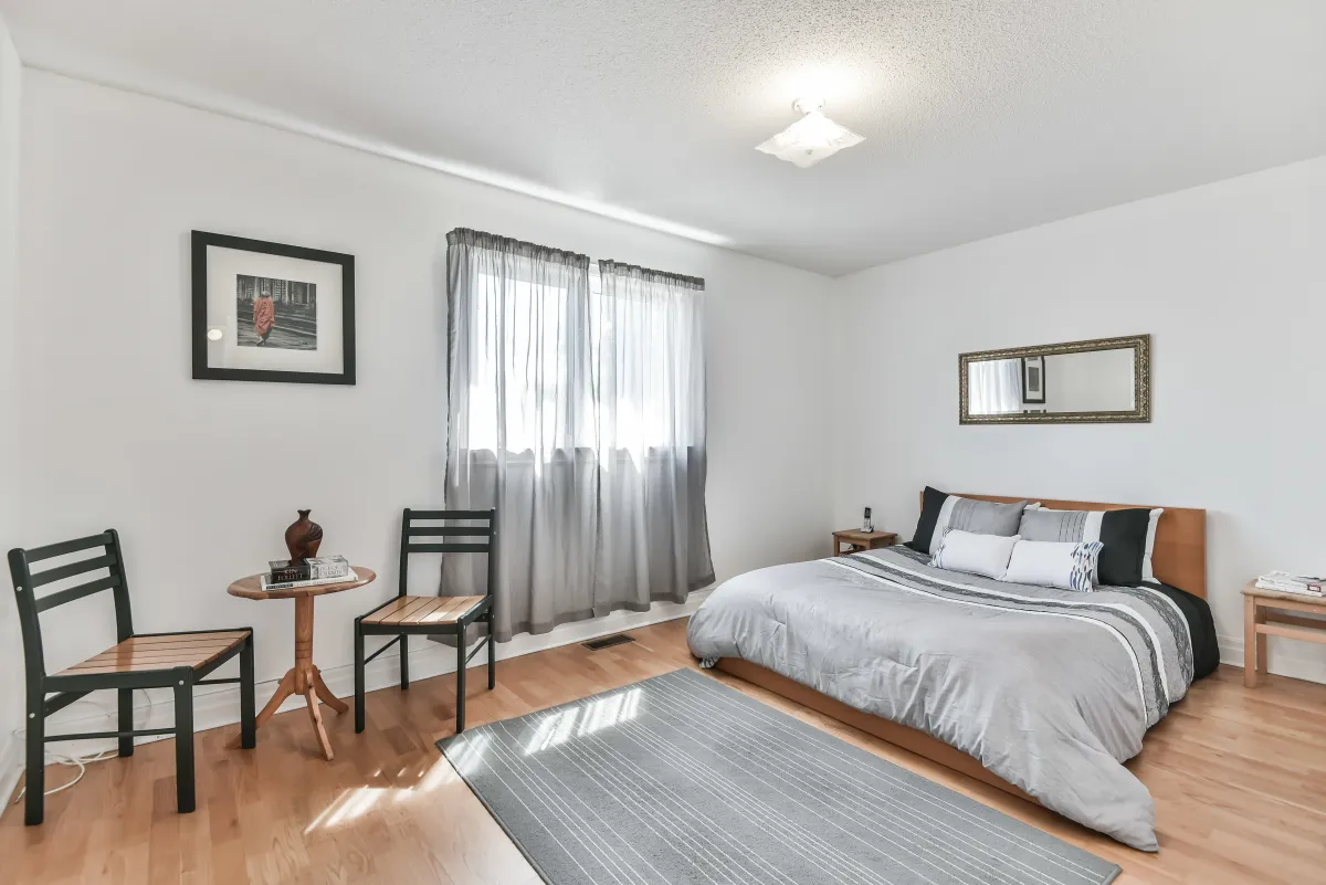 Spacious primary bedroom at 9 Algarve Cres, featuring a large window and warm hardwood flooring.