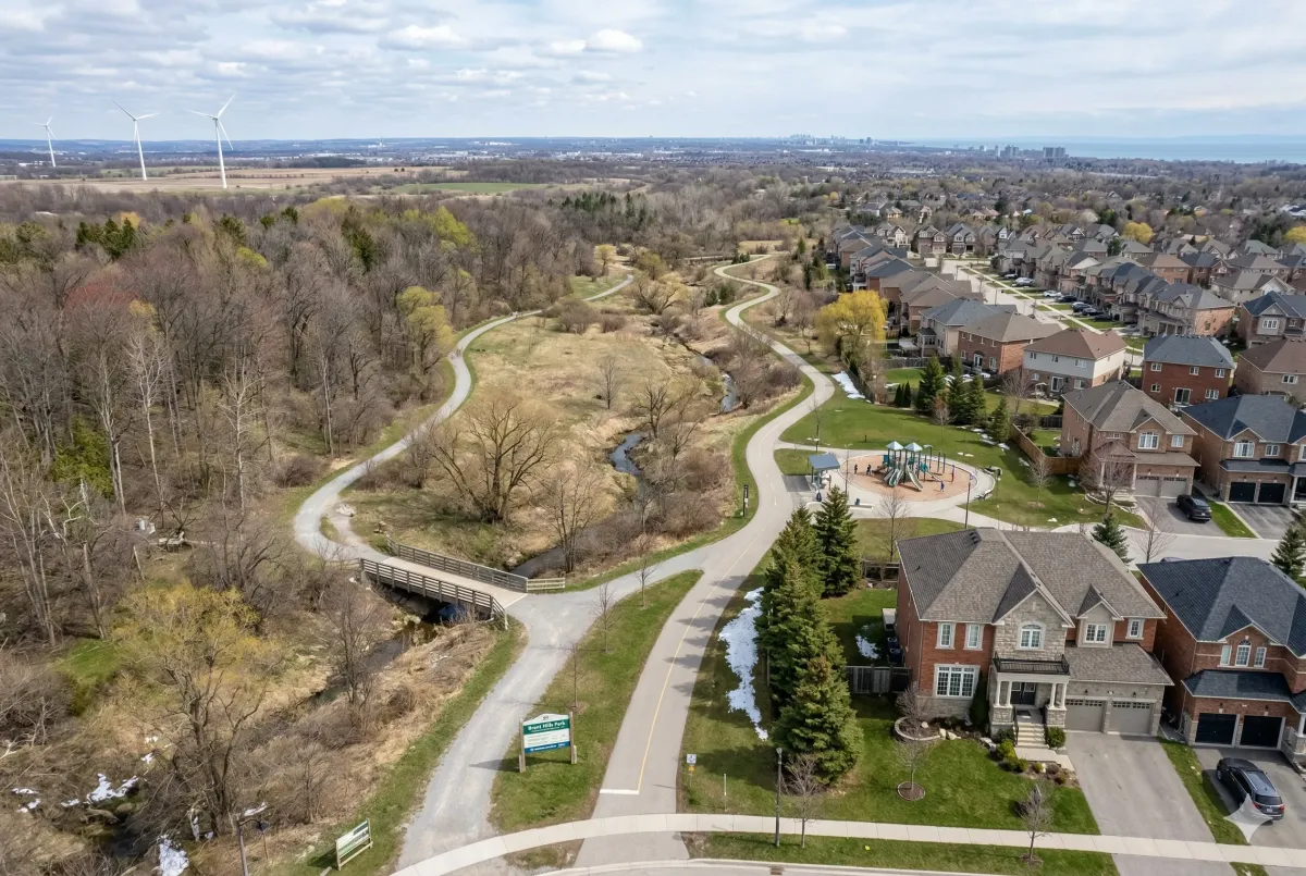 Quiet residential playground at Sinclair Park in the Brant Hills neighborhood, surrounded by mature trees and detached homes.
