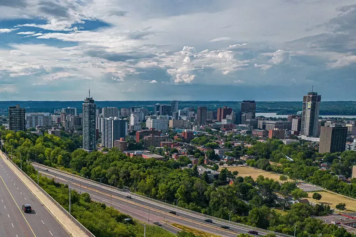 An expansive aerial view of the Hamilton city skyline and the surrounding Niagara Escarpment landscape.