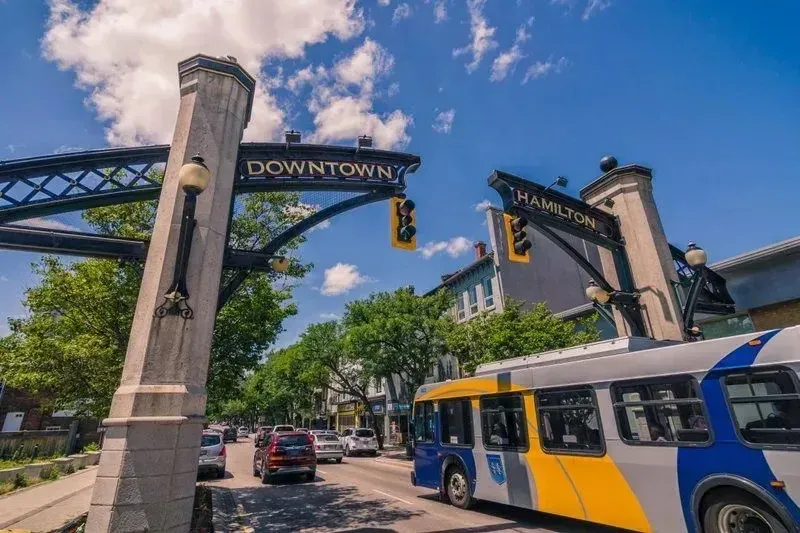 A city transit bus stopped at a downtown Hamilton intersection near public transportation infrastructure.