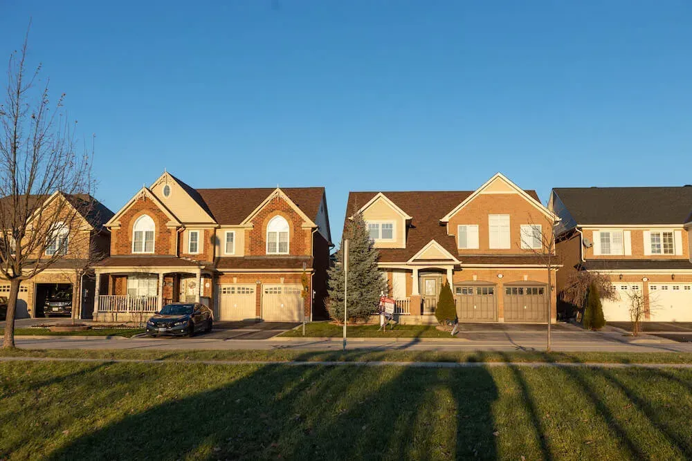 Row of matching brick detached houses in the Coates neighborhood at golden hour.