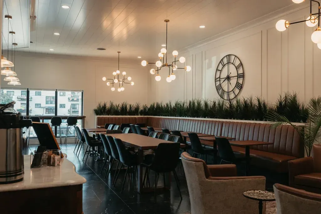 Clean, modern cafe interior with long banquet seating and industrial lighting.