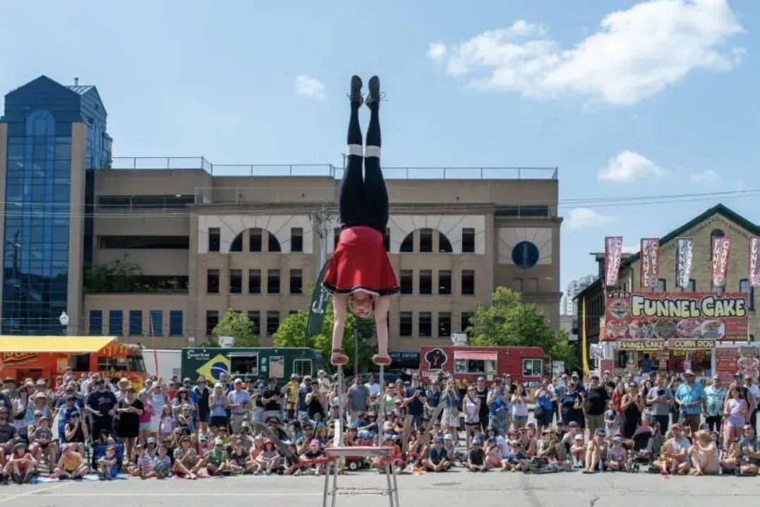 An acrobat performing a handstand on high poles for a crowd at the Waterloo Busker Carnival.
