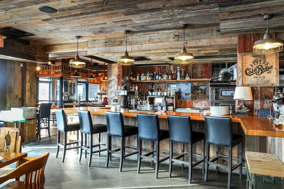 Rustic interior of Plank Restobar in Bronte Village featuring a wood-topped bar and industrial seating.