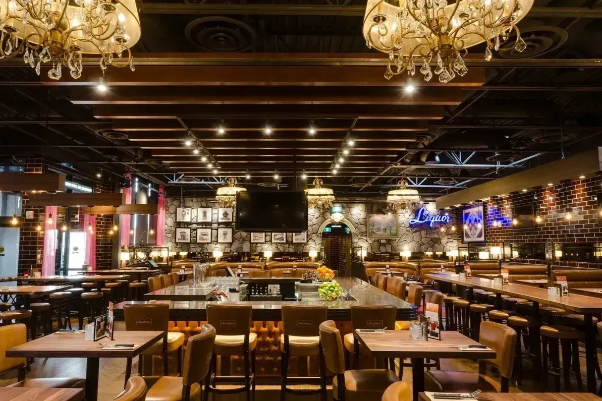Grand dining hall of Adonis Restaurant with ornate chandeliers and spacious table arrangements.