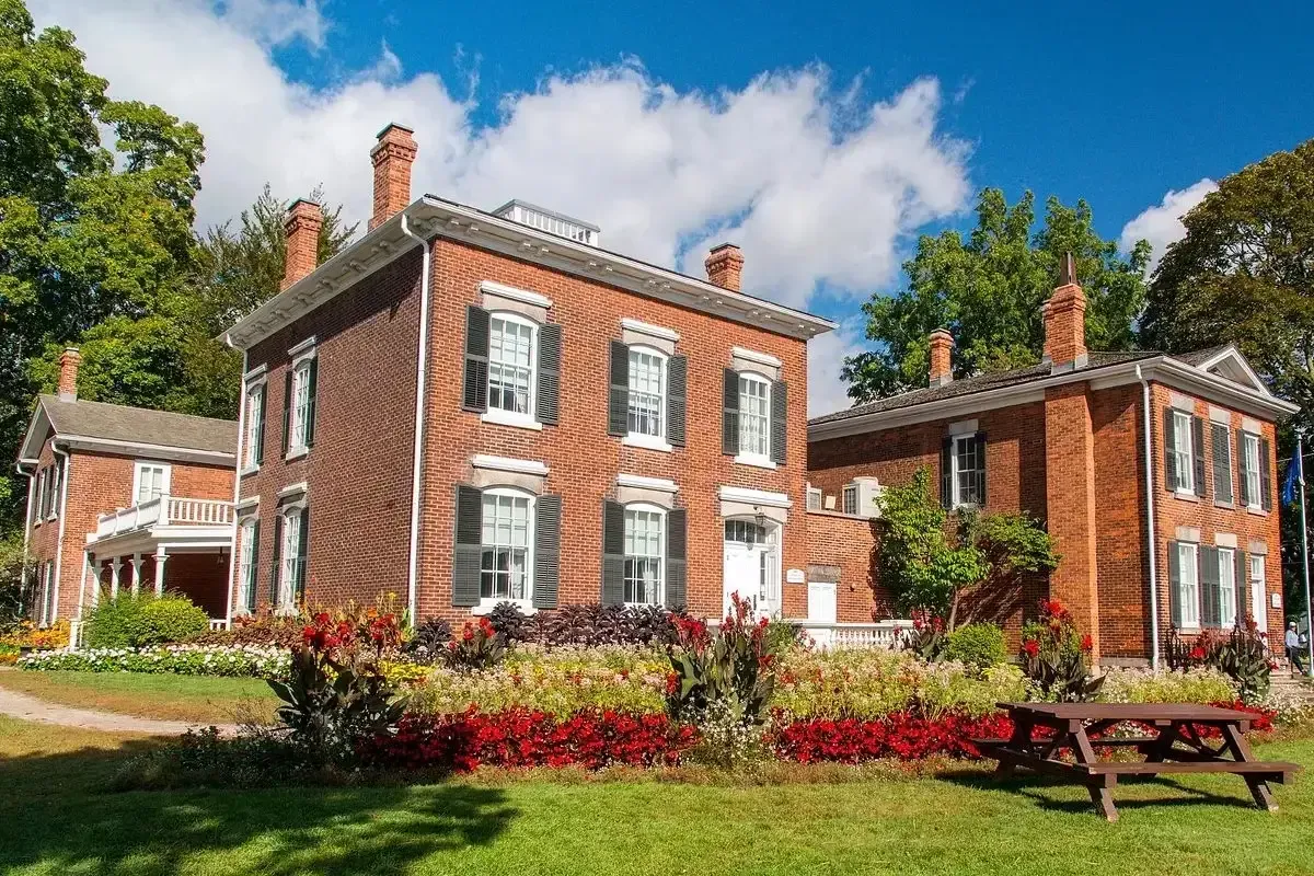 The historic brick facade of the Oakville Museum at Erchless Estate surrounded by gardens.
