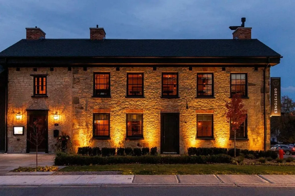 Historic stone exterior of Greystone Restaurant and Lounge with warm evening lighting.