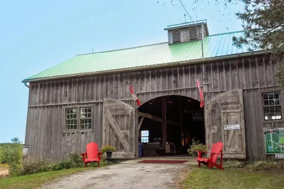 A large heritage barn with red chairs at the entrance of Elliott Tree Farm.