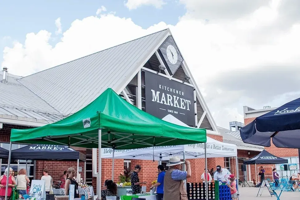 Outdoor stalls and green tents at the Kitchener Market, showcasing local vendors and fresh produce.