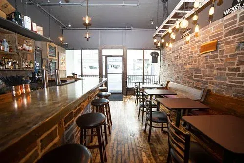 Moody and sophisticated interior of The Aging Oak wine and cocktail bar in Cambridge Ontario, featuring exposed brick.