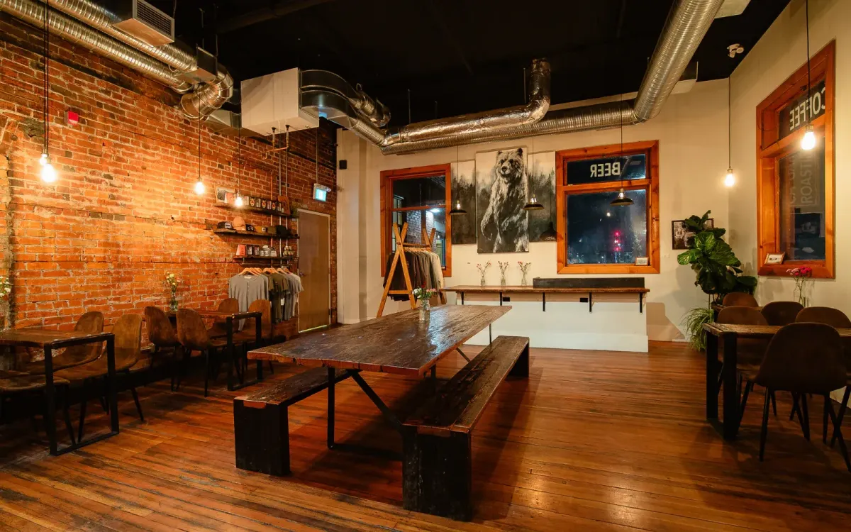 Rustic, brick-walled interior of Calgary Heritage Roasting Company, featuring long wooden communal tables.