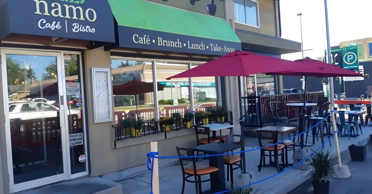 The exterior of Namo Cafe Bistro in Calgary, featuring a sidewalk patio and red umbrellas.