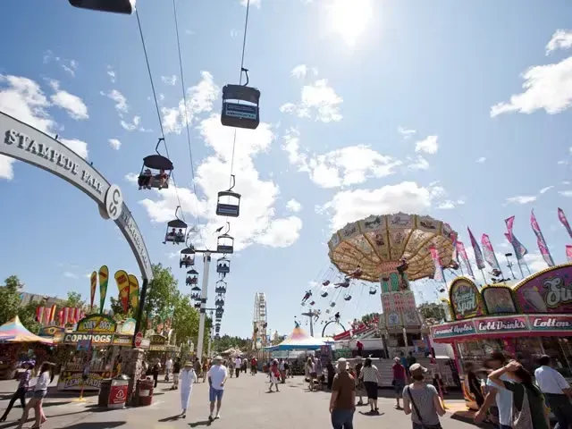 Vibrant summer crowds and amusement rides at the Calgary Stampede midway.