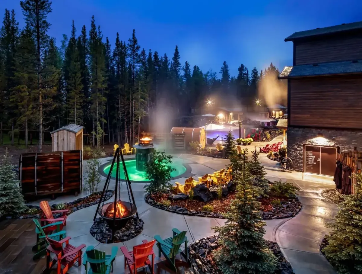 Outdoor hydrotherapy pools and fire pits at the Kananaskis Nordic Spa surrounded by evergreen trees.