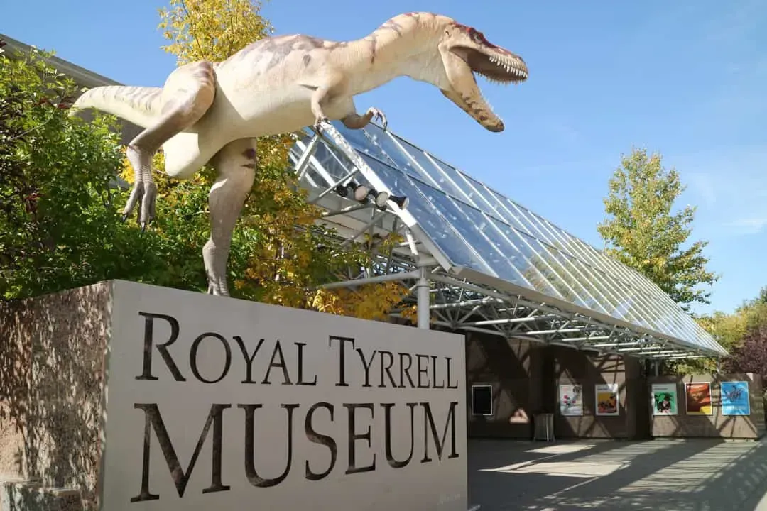 Exterior of the Royal Tyrrell Museum of Palaeontology in Drumheller, Alberta, featuring a large dinosaur statue.