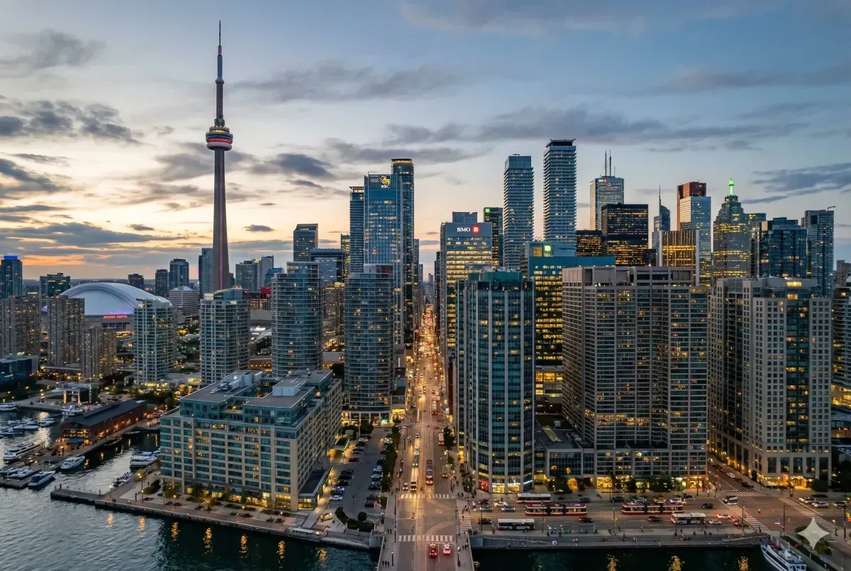 Panoramic Toronto city skyline at sunset featuring the CN Tower, Rogers Centre, and Lake Ontario waterfront, representing Canada's largest urban and financial hub.