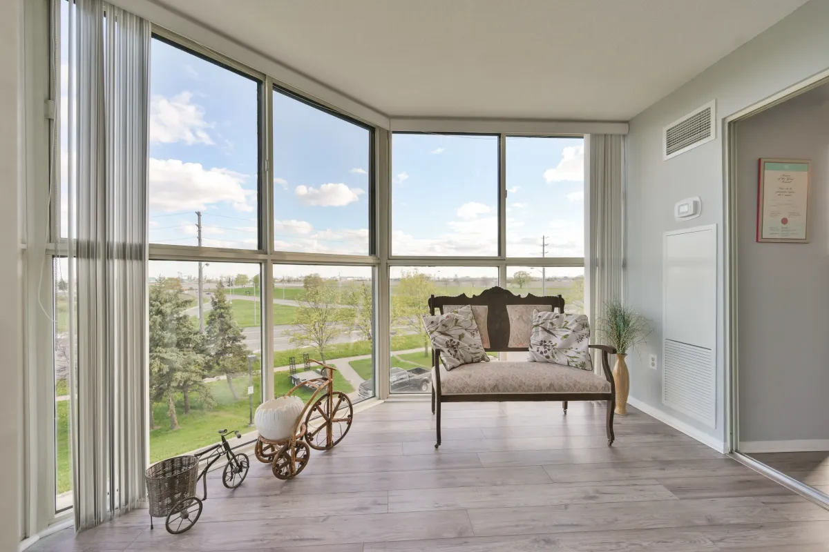 Bright enclosed solarium with large windows overlooking green space at 600 Rexdale Blvd.