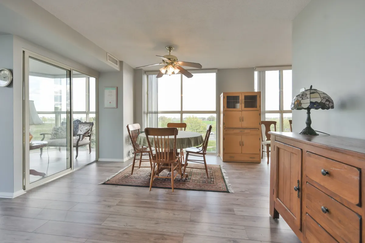 Open concept dining area with hardwood floors and ceiling fan near large windows.