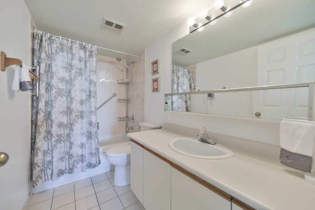 Clean and bright bathroom featuring a large vanity mirror and bathtub