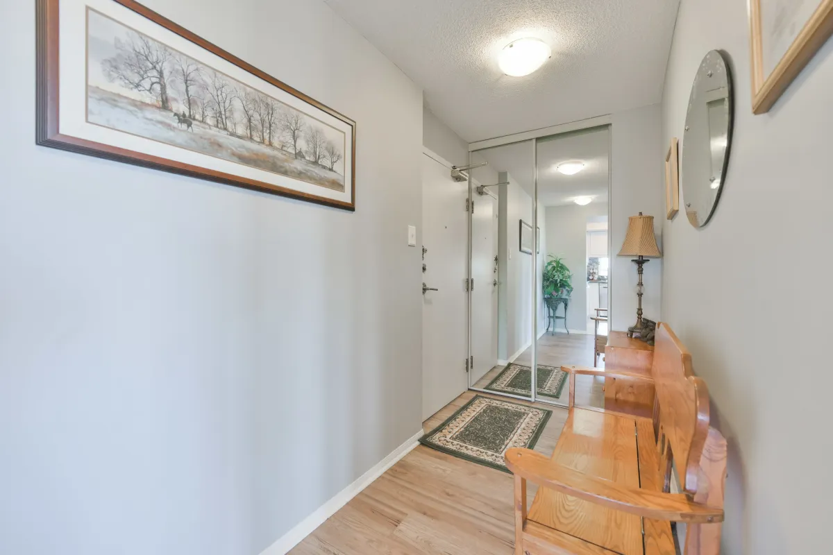 Bright condo entrance foyer with mirrored closets and laminate flooring.