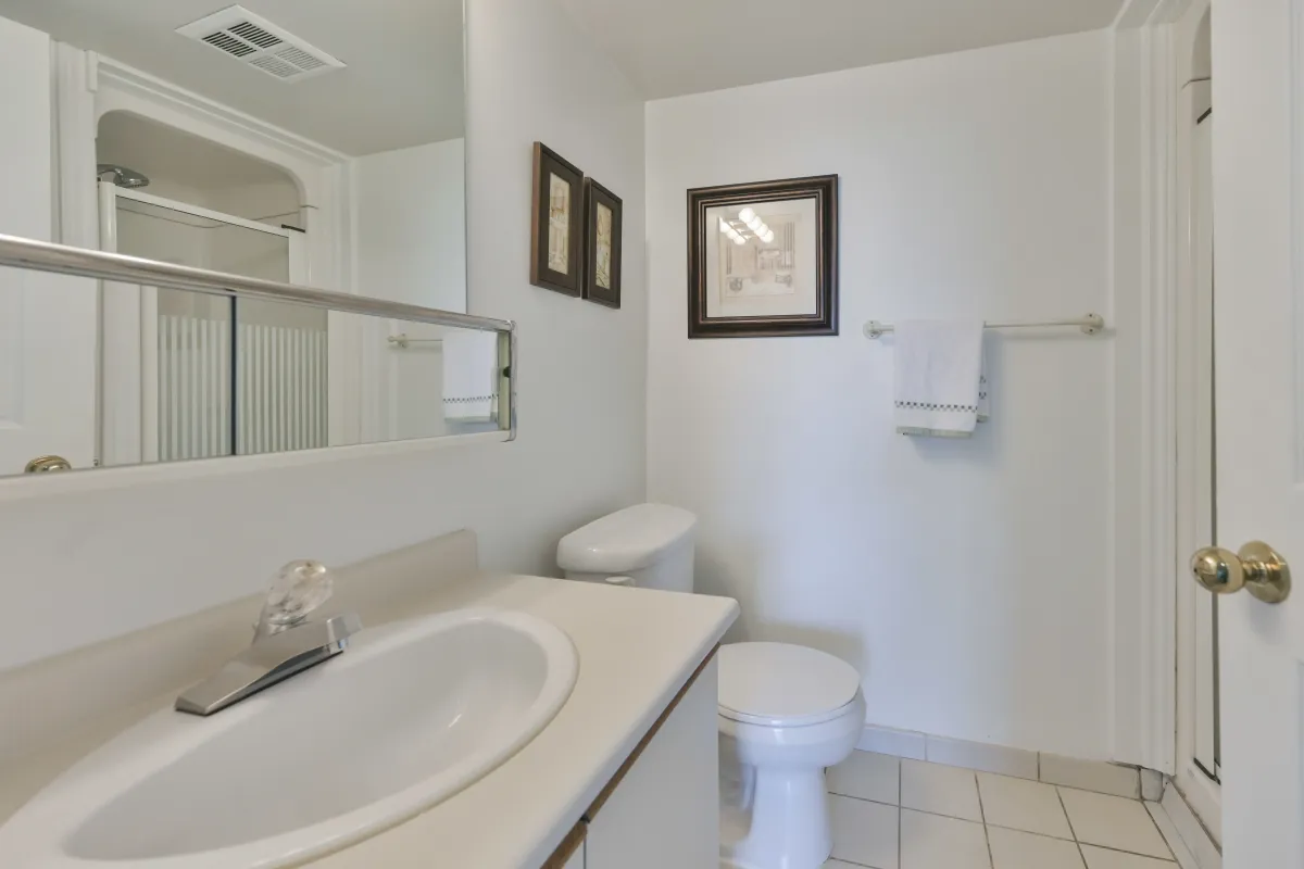 Clean and bright bathroom featuring a large vanity mirror and integrated shower.