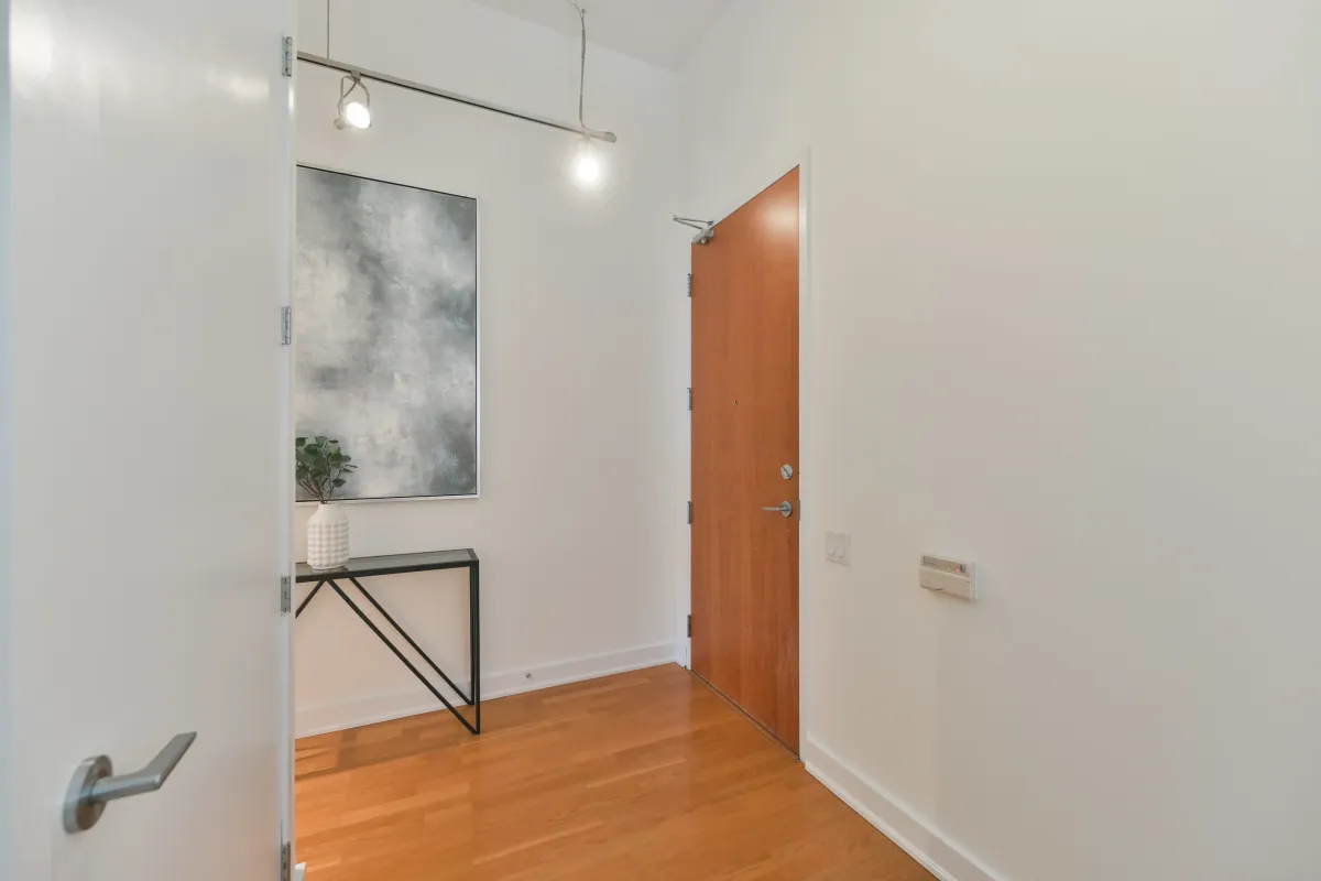 Interior condo hallway showing a wood-toned door and track lighting at 61843 Hanna Ave.