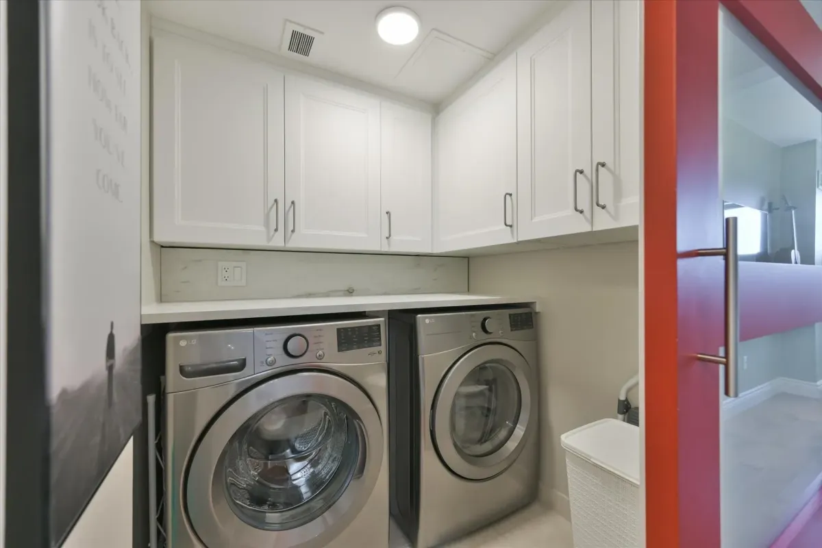 Front-loading washer and dryer set up beneath custom white storage cabinetry inside 240 Scarlett Rd #912.