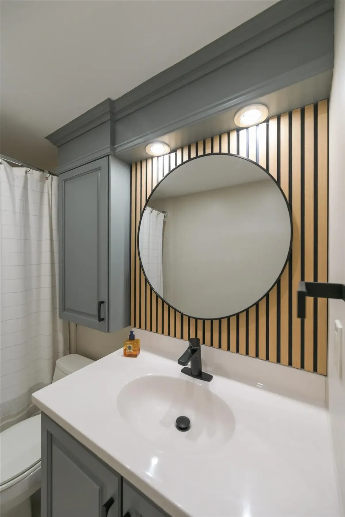 Custom grey crown molding and vanity light details above the round mirror in the bathroom of 240 Scarlett Rd #912.