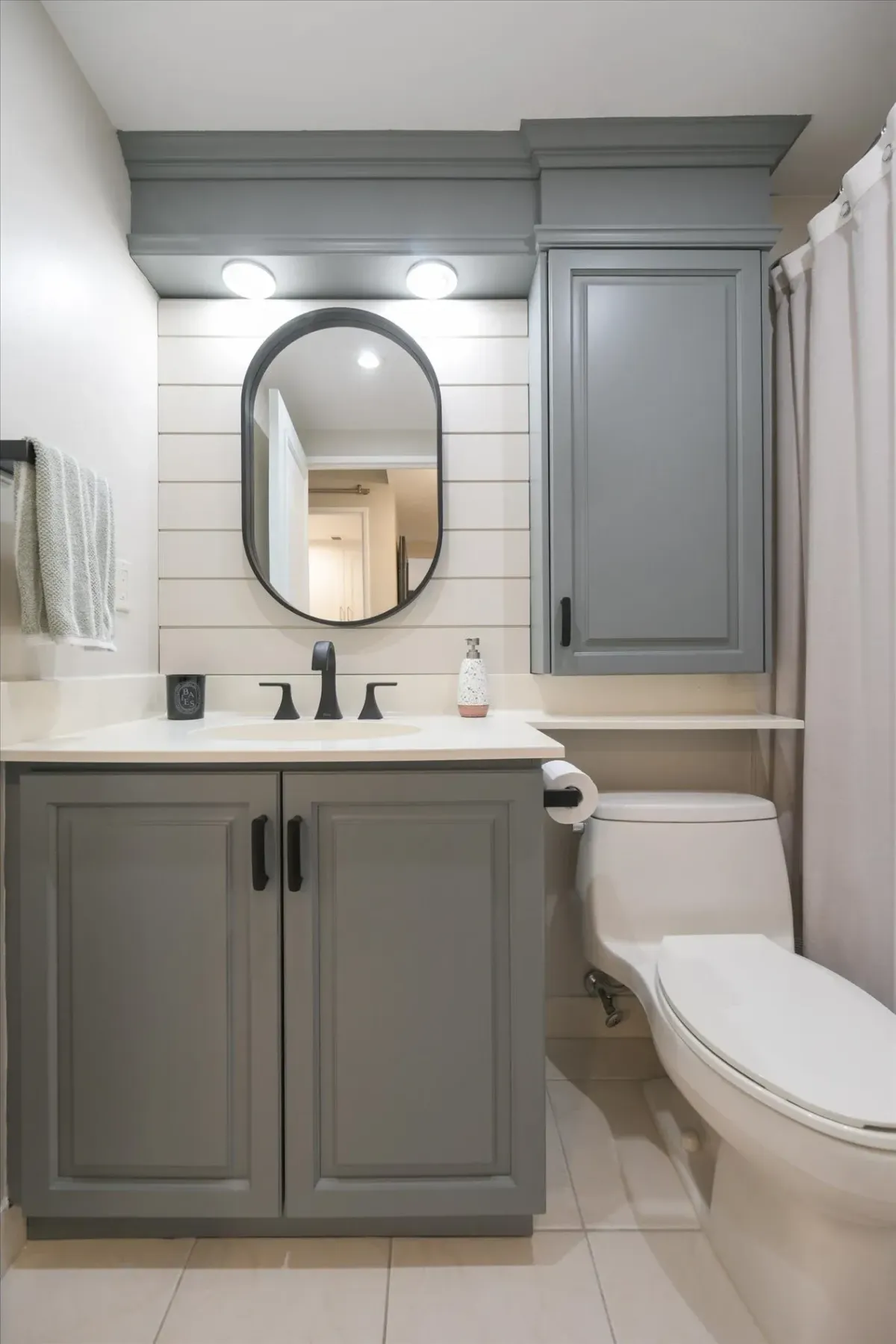 Symmetric straight-on shot of the modern vanity area, round mirror, and custom grey cabinetry at 240 Scarlett Rd #912.