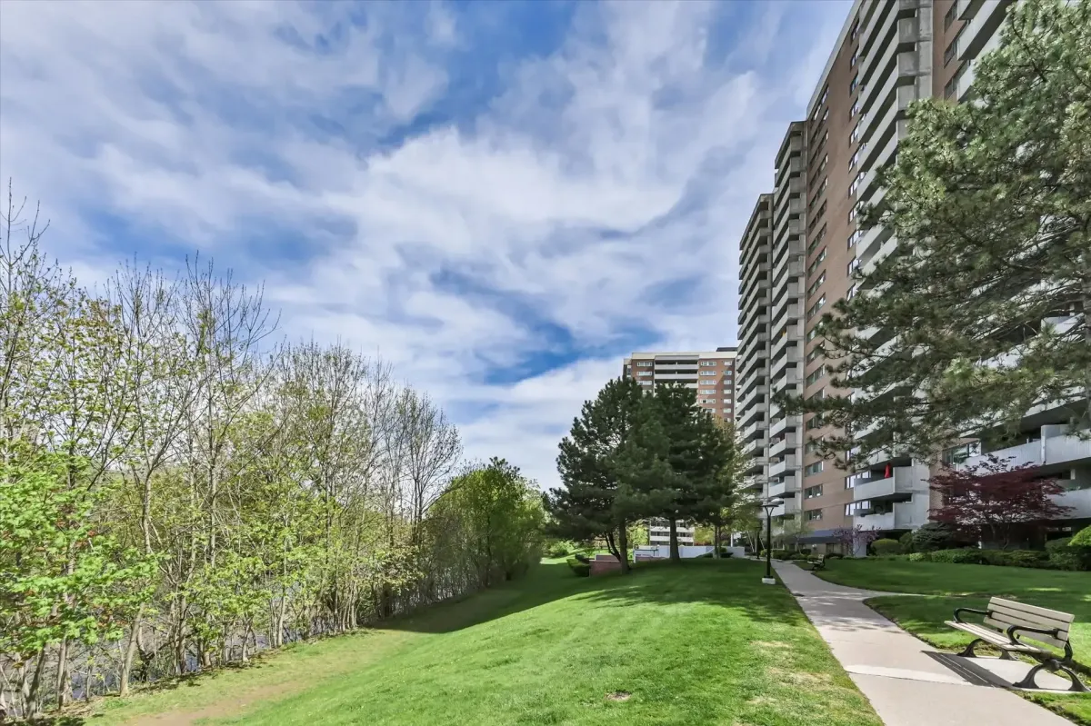 Looking up from the landscaped grounds at the side profile of the high-rise condo building at 240 Scarlett Rd #912 against a blue sky.