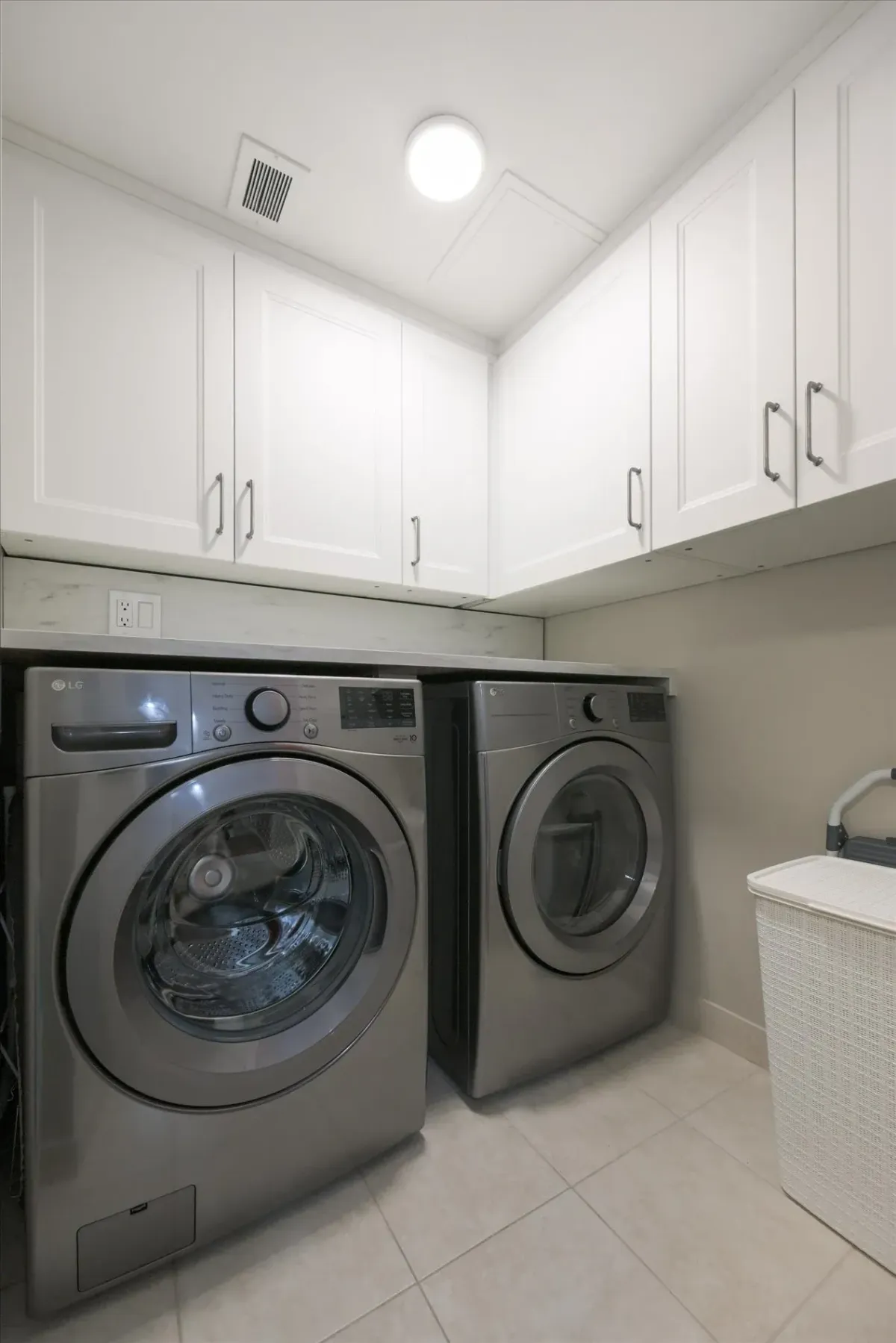 In-suite laundry area at 240 Scarlett Rd #912 highlighting white upper storage cabinets and under-counter washer and dryer.