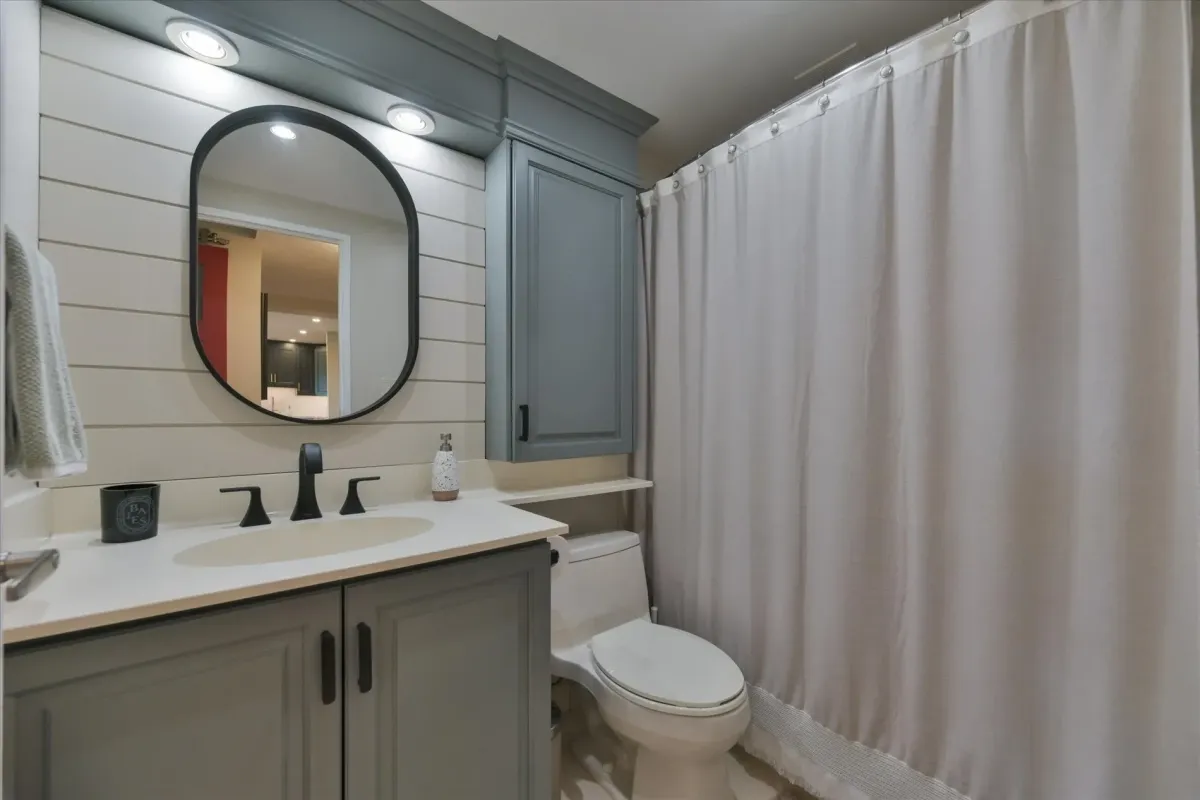 Second full bathroom at 240 Scarlett Rd #912 featuring a grey vanity, round mirror, white tiled walls, and a shower curtain.