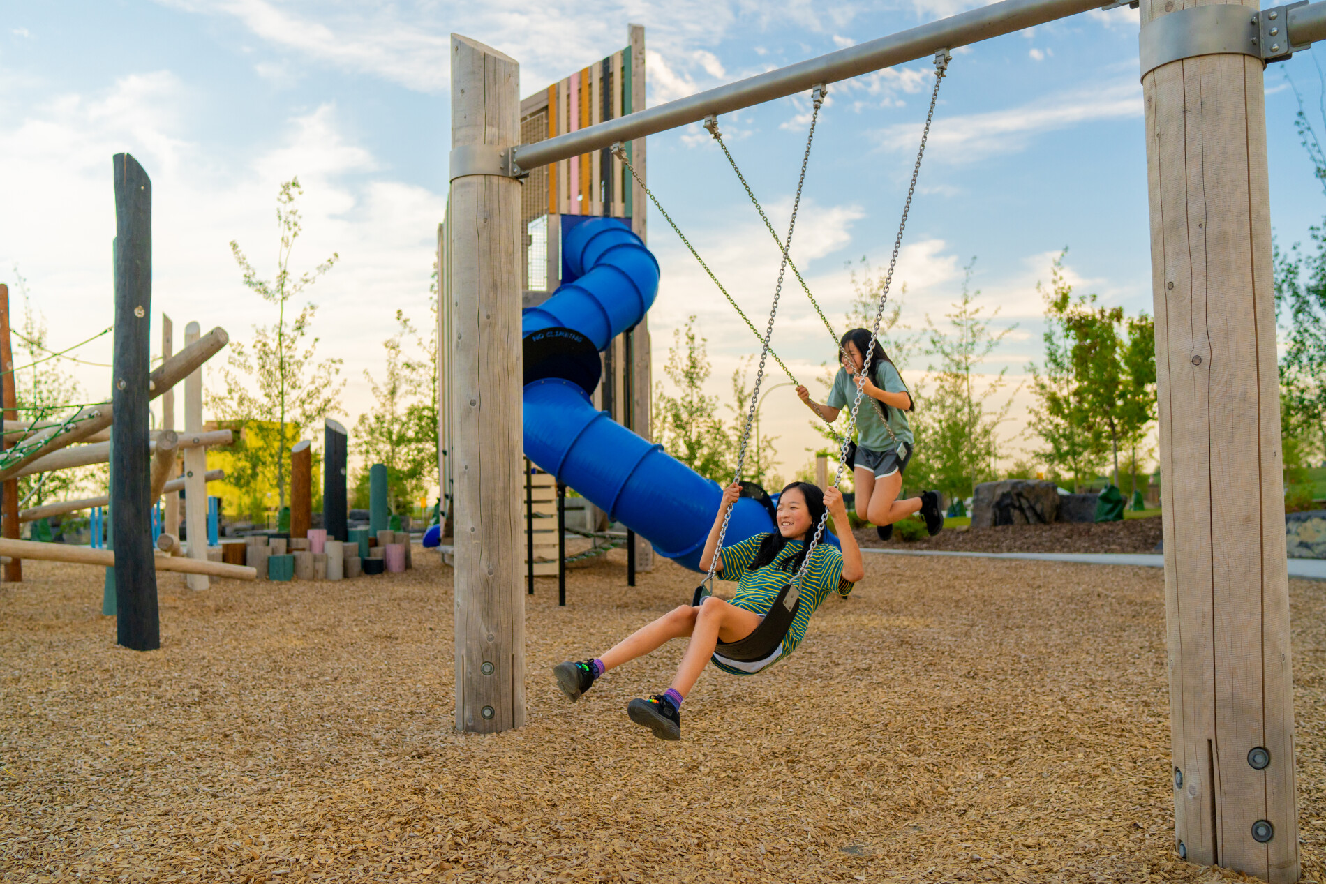 15020 Bow Trail SW Alpine Park Calgary children playing on blue slide and swings at community green space park
