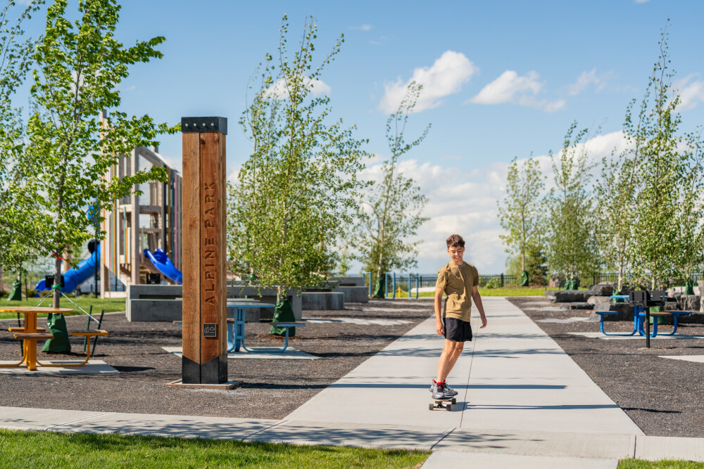 15020 Bow Trail SW Alpine Park Calgary child skateboarding at local community park playground and pathway network