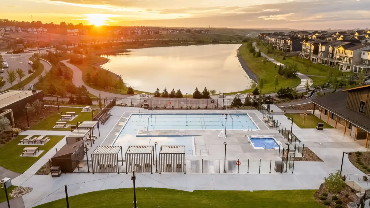 Rockland Park NW Calgary fenced outdoor swimming pool overlooking a neighborhood stormwater pond at sunset.