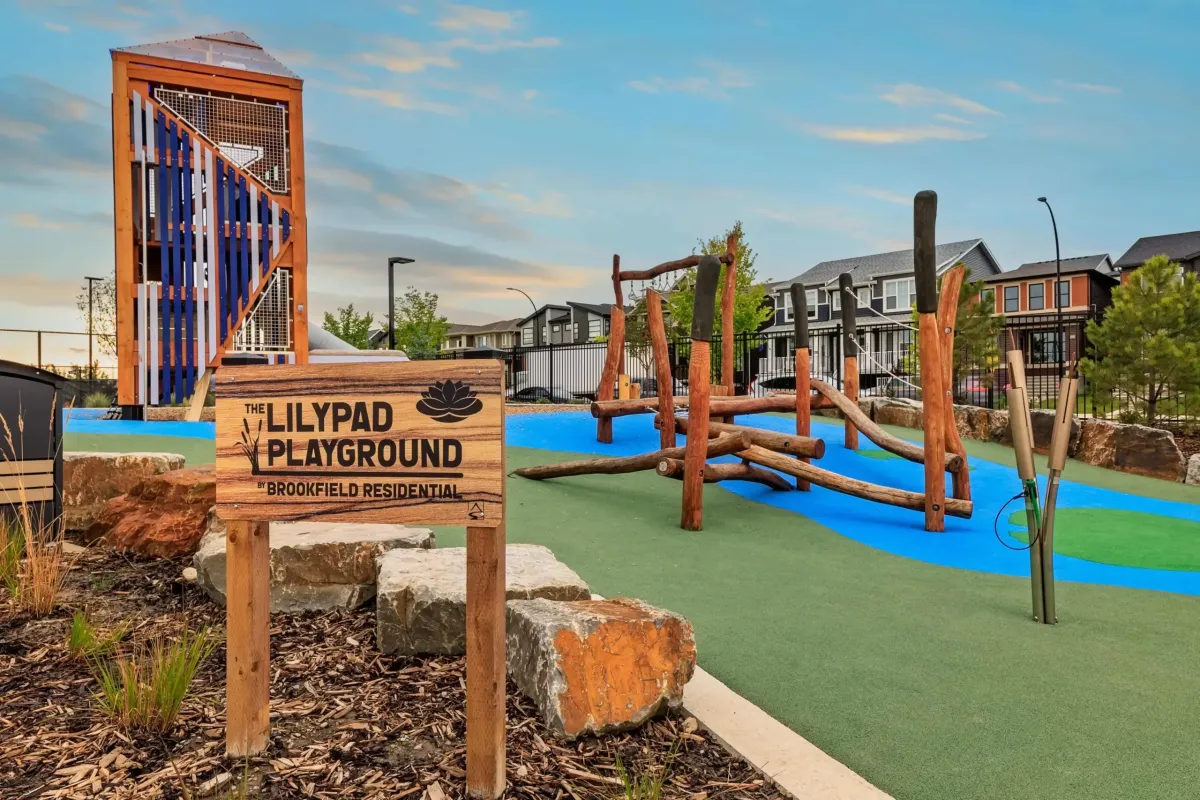 Rockland Park NW Calgary The Lilypad Playground wooden sign by Brookfield Residential with play structures in the background.